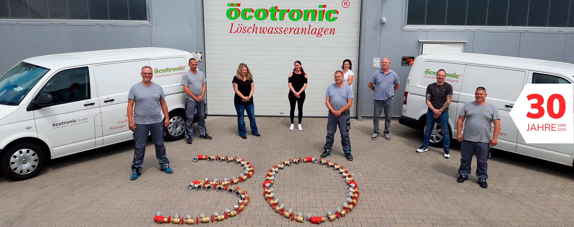 30 Jahre Öcotronic Aussenaufnahme der Firma mit Mitarbeitern und Firmenfahrzeugen